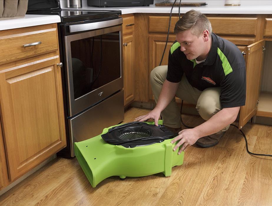 Technician setting air mover in kitchen